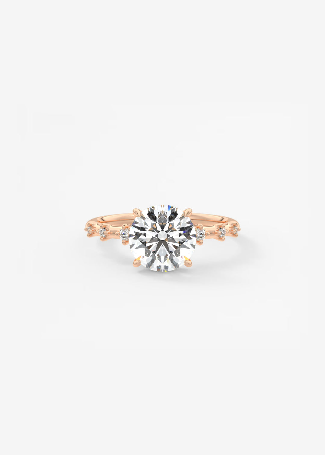 A rose gold engagement ring featuring a large round-cut clear center stone and smaller side stones, photographed on a clean white background.#material_rose