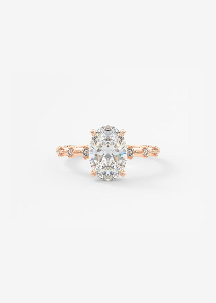A rose gold engagement ring featuring a large oval-cut center stone and small accent stones along the band, set against a plain white background.#material_rose