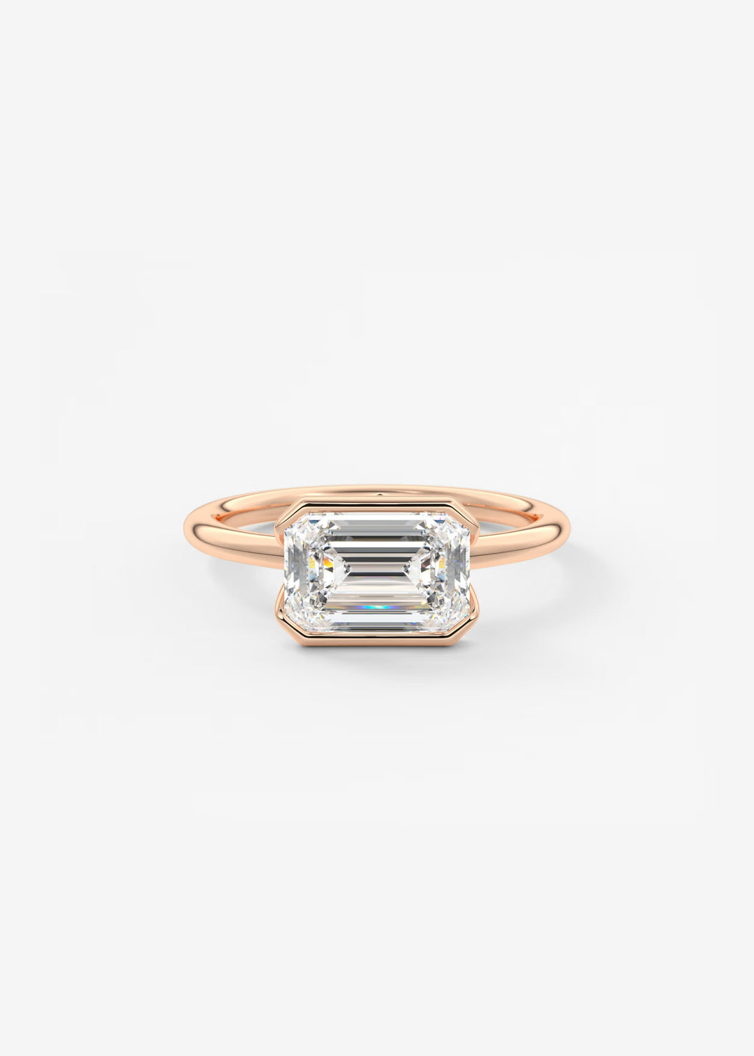 A rose gold ring featuring a large rectangular emerald-cut clear gemstone in a bezel setting, shown against a plain white background.#material_rose