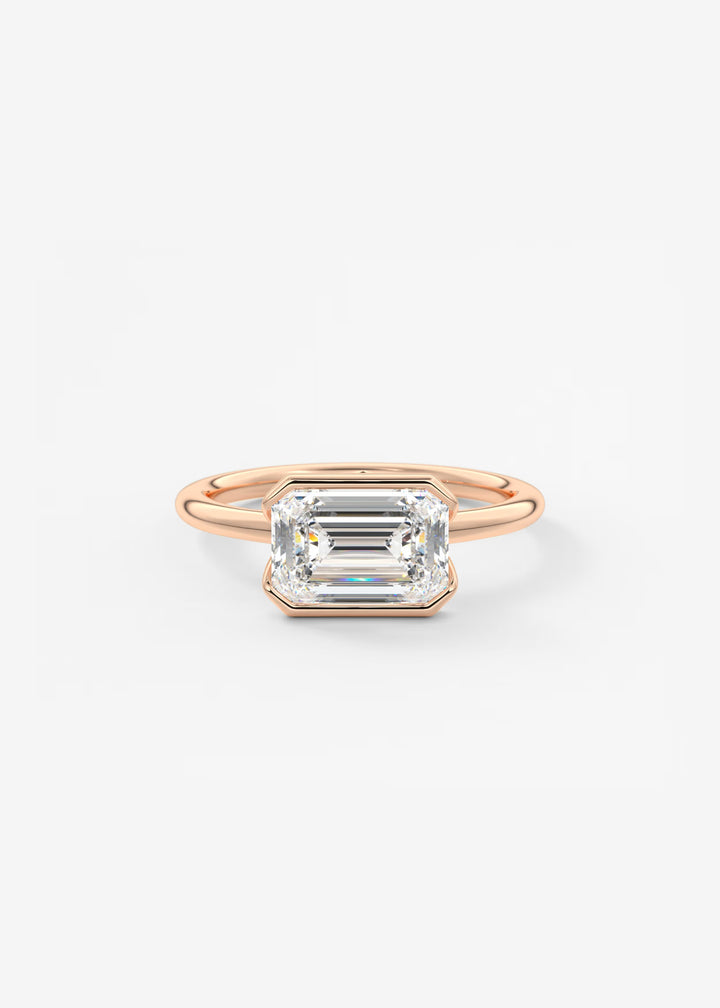 A rose gold ring featuring a large rectangular emerald-cut clear gemstone in a bezel setting, shown against a plain white background.#material_rose