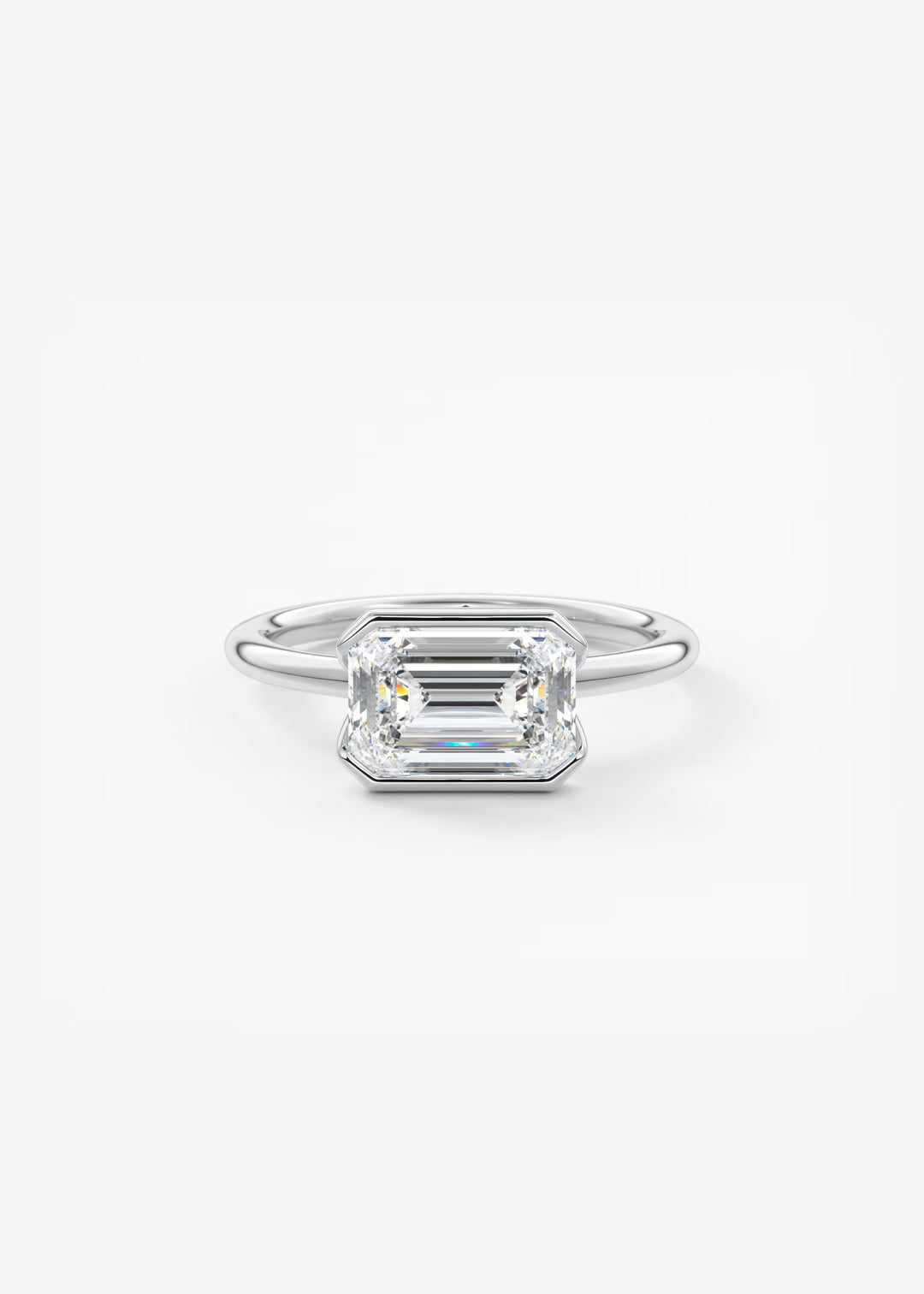 An emerald-cut diamond engagement ring in a silver-colored metal band, centered on a clean white background. #material_white