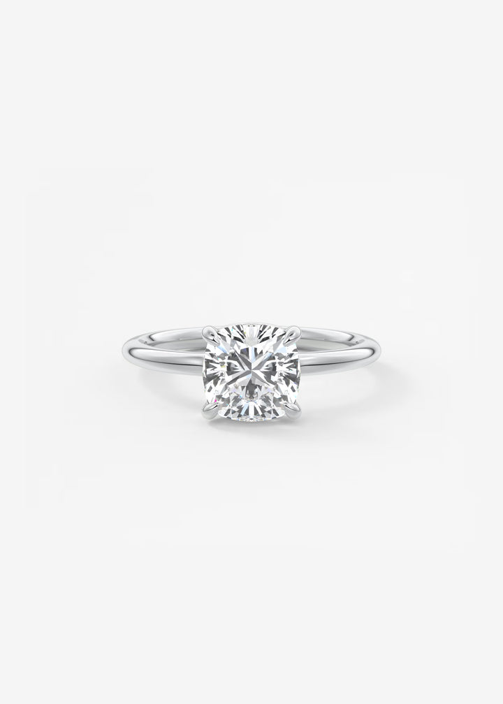A classic solitaire engagement ring featuring a round brilliant-cut diamond set in a polished silver-colored metal band, centered on a clean white background.#material_white
