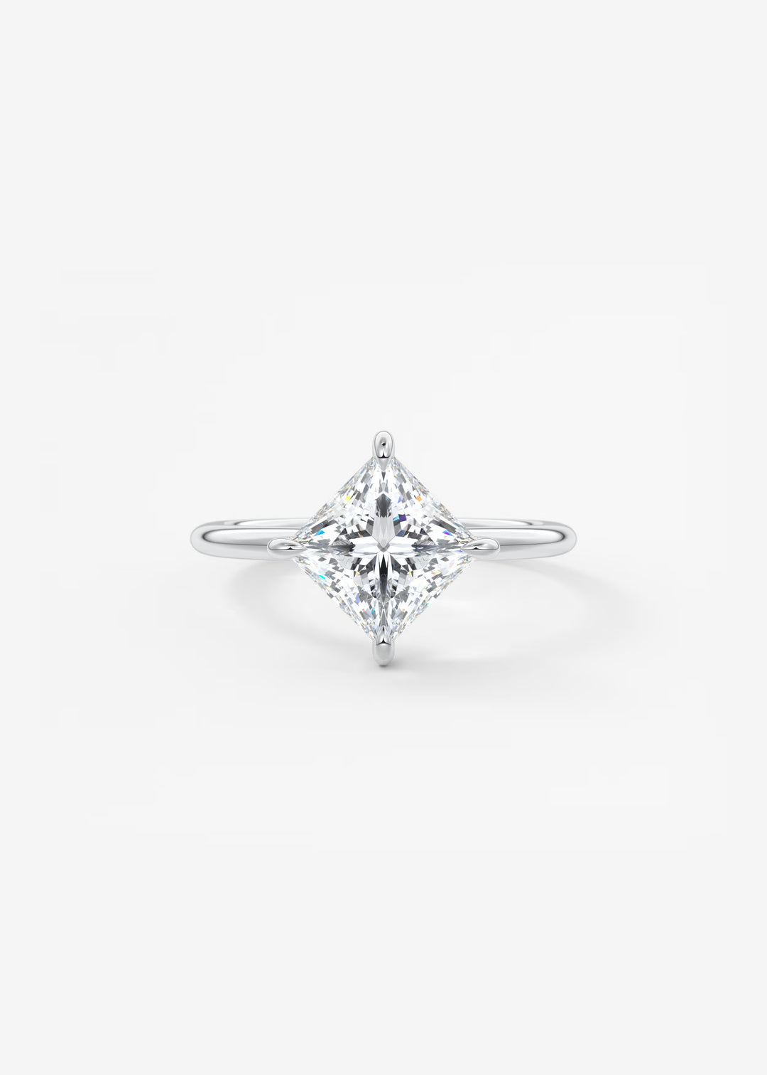 A diamond engagement ring featuring a brilliant round-cut center stone in a four-prong setting on a slim silver band, photographed against a clean white background.#material_white