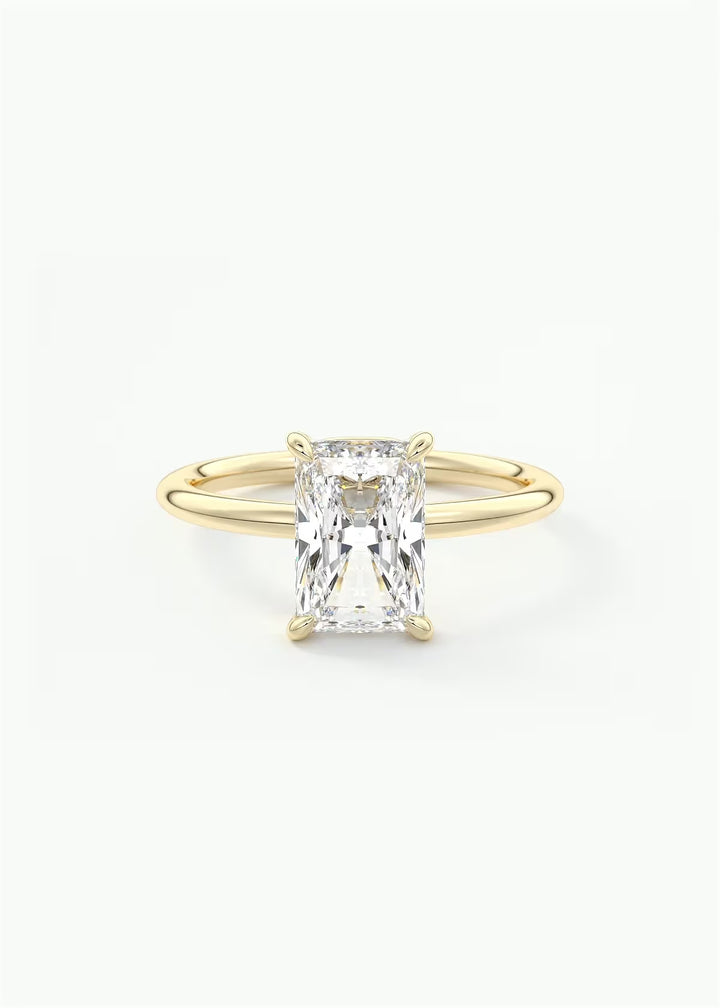 A yellow gold ring featuring a large rectangular emerald-cut clear gemstone in a four-prong setting, shown against a plain white background.#material_gold