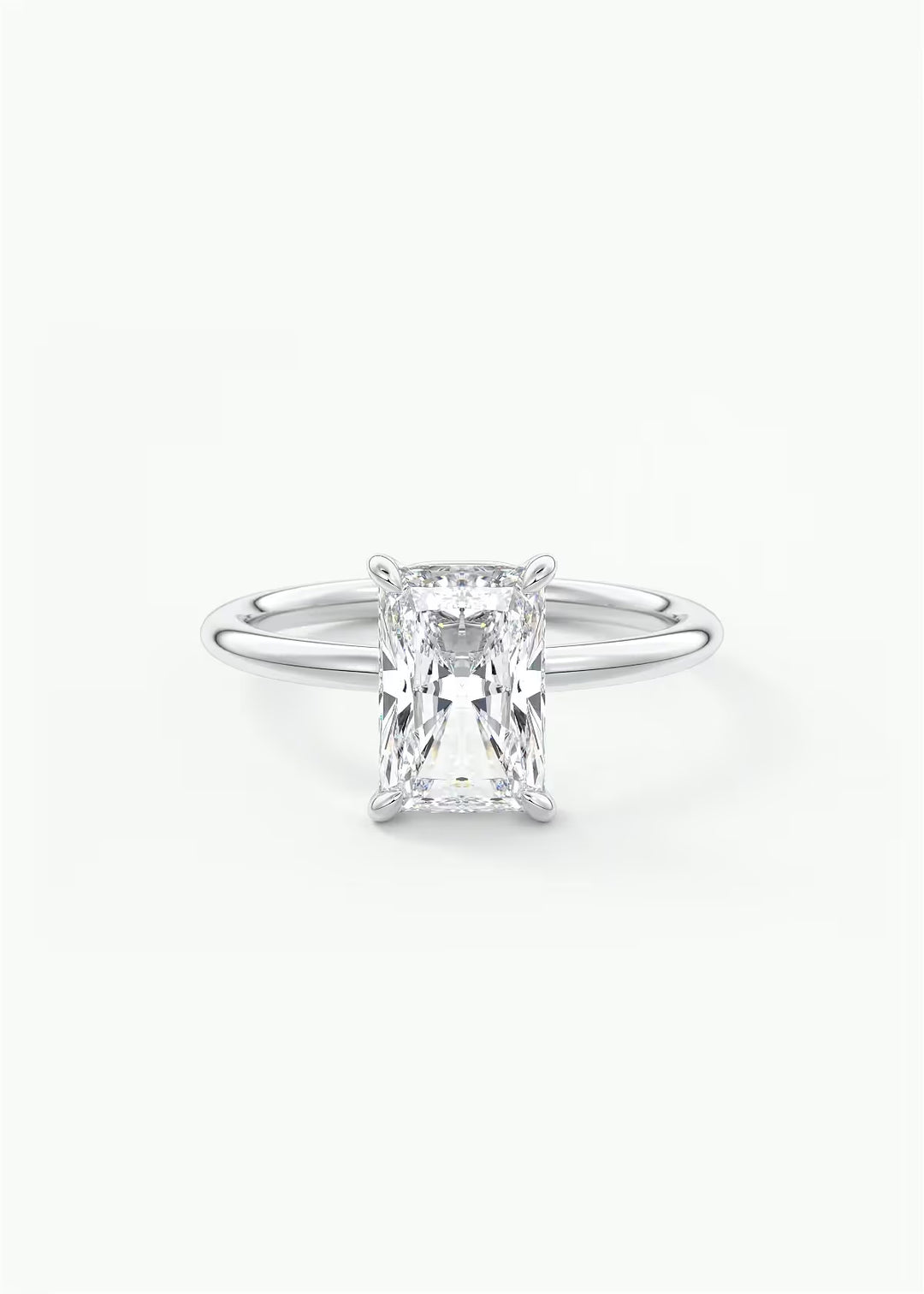 A silver solitaire engagement ring featuring a rectangular emerald-cut diamond, set against a clean white background. #material_white