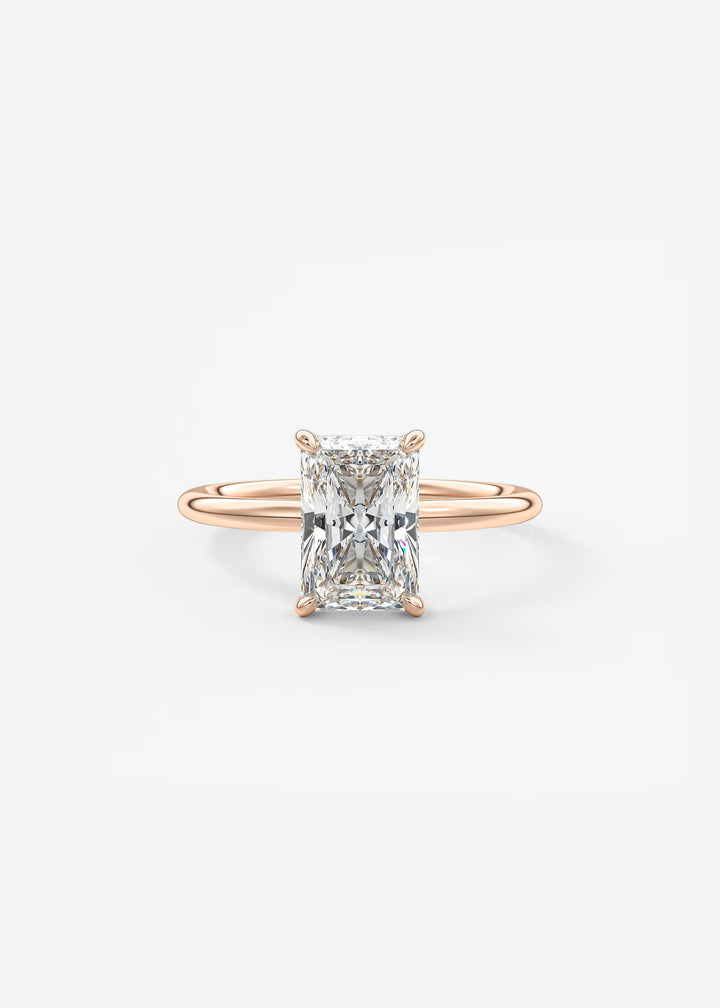 A rose gold engagement ring featuring a rectangular radiant-cut diamond center stone in a four-prong setting, shown on a clean white background.#material_rose