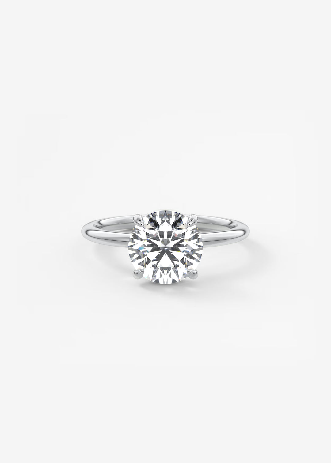 A classic solitaire engagement ring featuring a round brilliant-cut diamond set in a polished silver-colored metal band, centered on a clean white background.#material_white