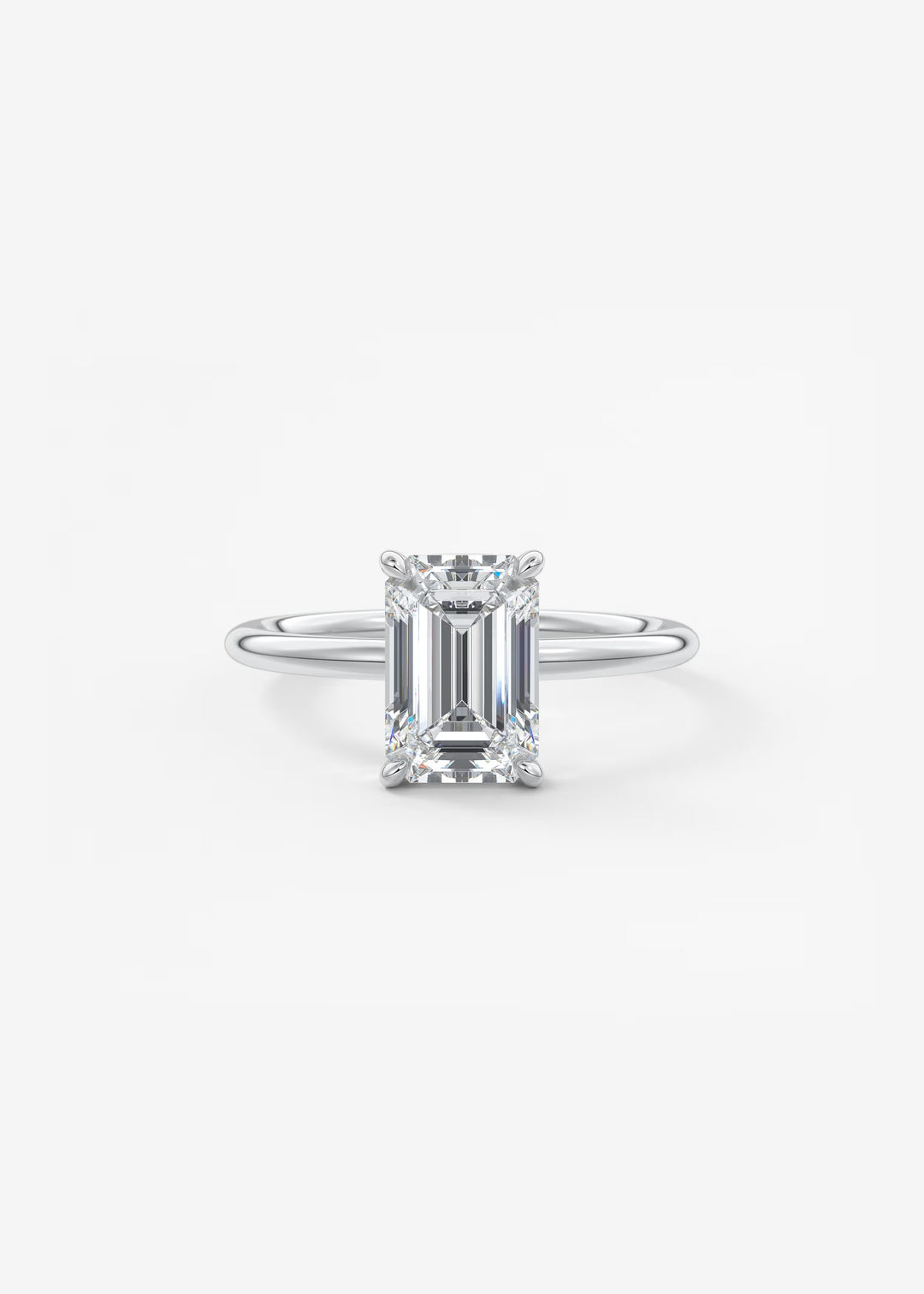 An emerald-cut diamond solitaire ring in a silver-colored metal setting, centered on a clean white background.#material_white