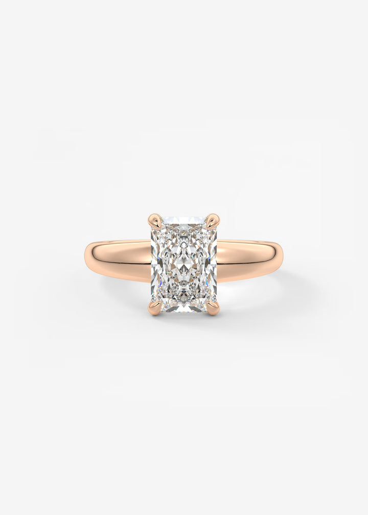 A rose gold solitaire ring featuring a large rectangular radiant-cut diamond, set against a clean white background.#material_rose