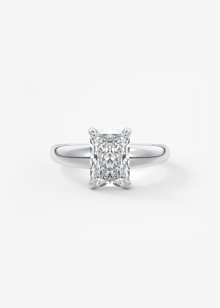 An engagement ring featuring a rectangular radiant-cut diamond set in a polished silver-colored band, centered on a clean white background.#material_white