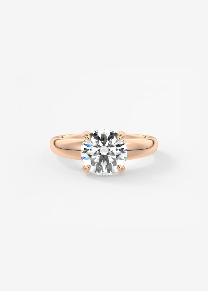 A classic solitaire engagement ring featuring a round brilliant-cut diamond set in a rose gold four-prong band, centered on a clean white background.#material_rose