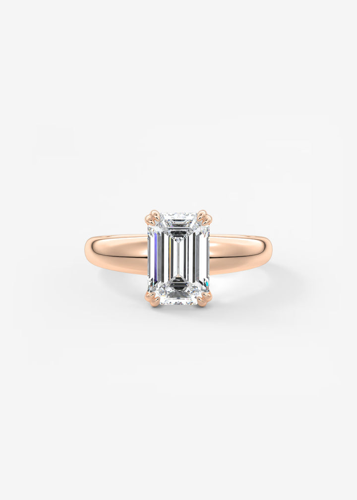 A rose gold ring with a large emerald-cut clear gemstone, set against a clean white background.#material_rose