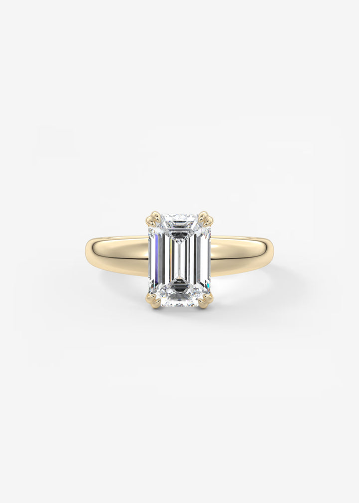 A rose gold ring with a large emerald-cut clear gemstone, set against a clean white background.#material_gold