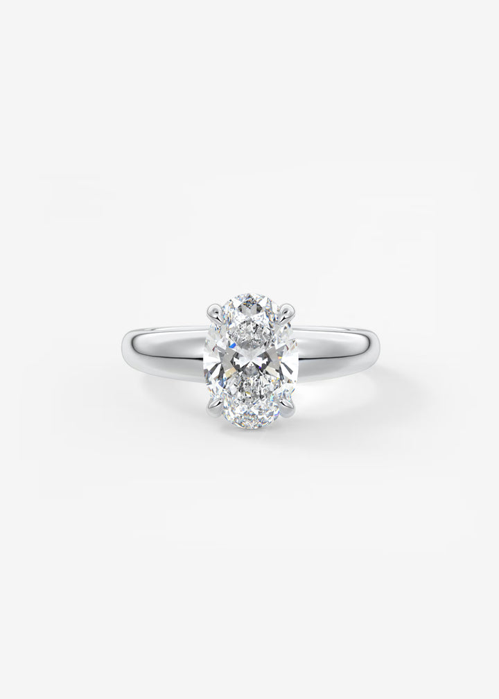 A classic solitaire engagement ring featuring a round brilliant-cut diamond set in a polished white gold or platinum band, centered on a clean white background.#material_white