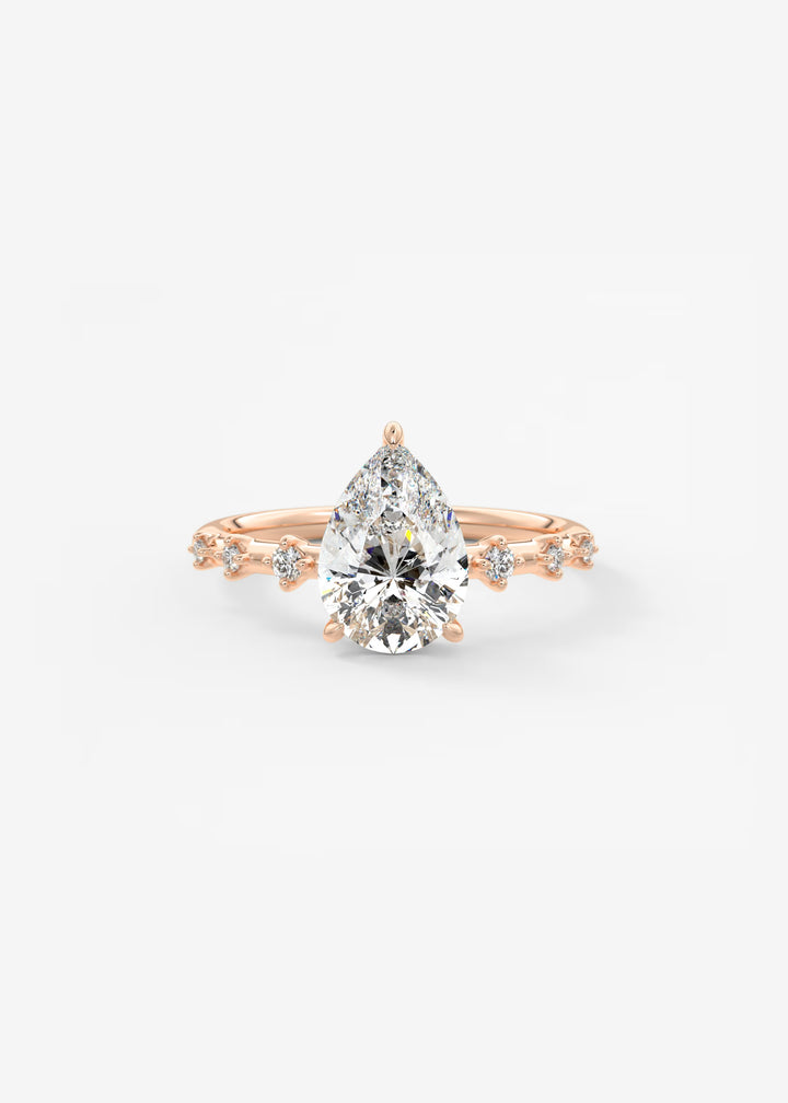 A pear-cut diamond engagement ring in rose gold, featuring a central diamond and smaller diamonds along the shoulders of a delicate rose gold band, set against a clean white background.#material_rose