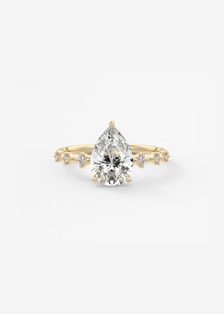 A pear-cut diamond engagement ring in yellow gold, featuring a central pear-shaped diamond and smaller diamonds along the shoulders of the band, set against a clean white background.#material_gold