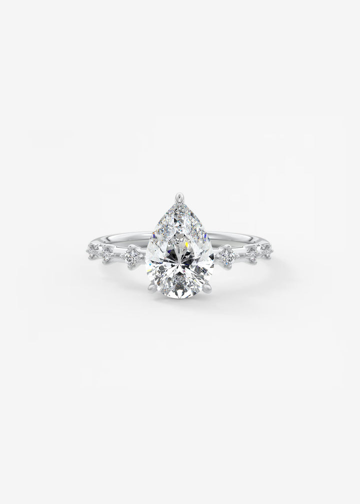A pear-cut diamond engagement ring with a brilliant center stone and small side diamonds on a white background.#material_white