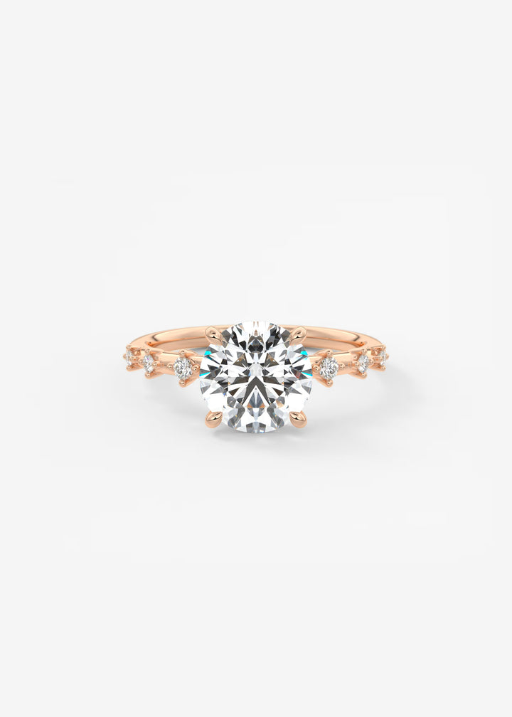 A rose gold engagement ring featuring a large round brilliant-cut center stone and smaller accent stones along the shoulders, set against a clean white background.#material_white