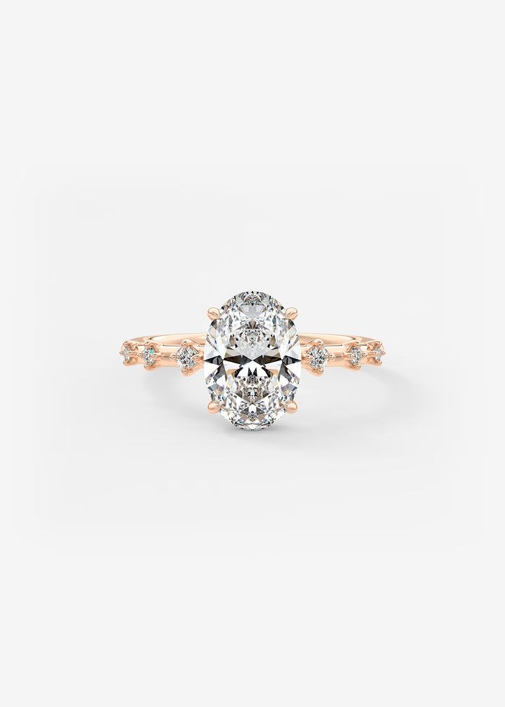 A rose gold engagement ring featuring a large oval-cut center stone and small accent stones along the shoulders, set against a clean white background.#material_rose