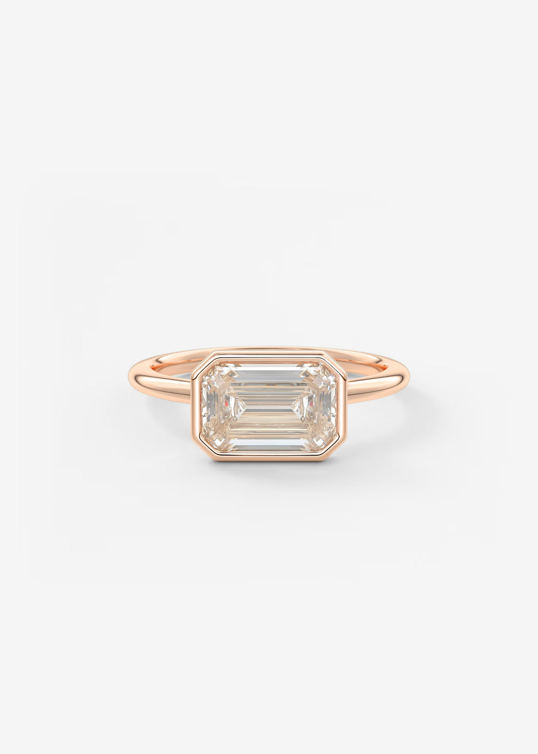 A rose gold ring featuring a large rectangular emerald-cut clear gemstone in a bezel setting, shown against a plain white background.#material_rose
