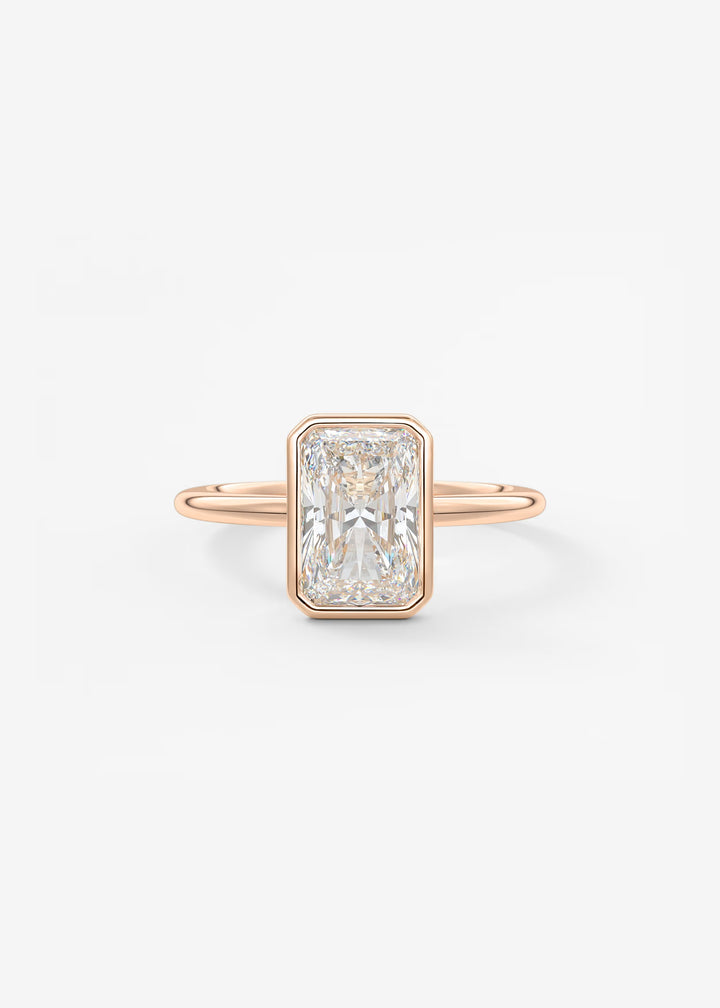 A rectangular emerald-cut diamond ring set in a rose gold band, centered on a clean white background.#material_rose