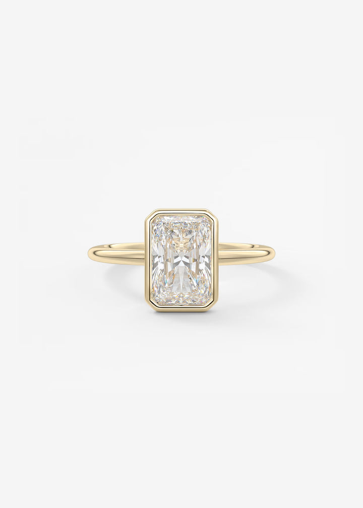 A yellow gold ring featuring a rectangular emerald-cut diamond center stone, set against a clean white background.#material_gold