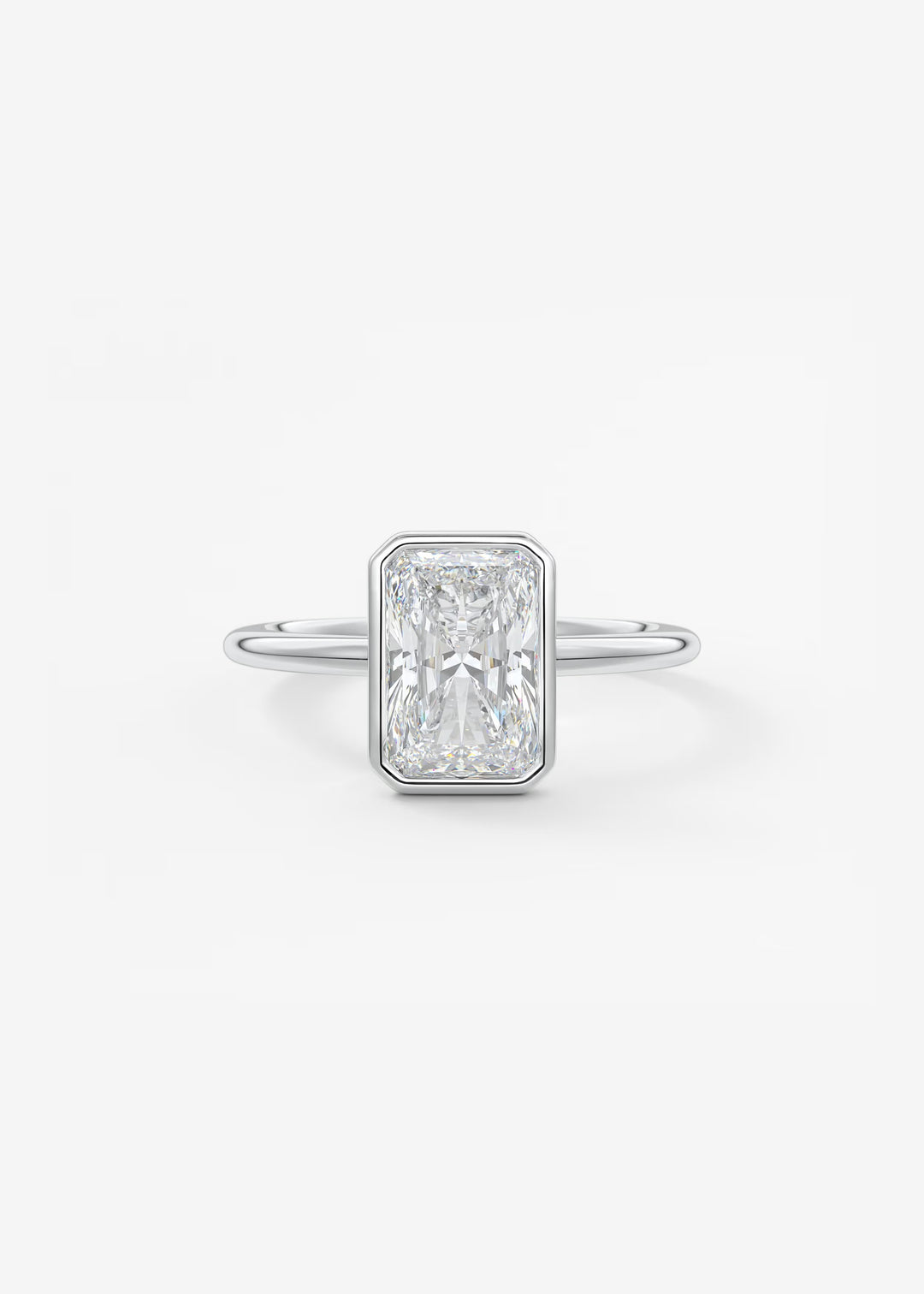 A silver-toned ring featuring a rectangular baguette-cut diamond center stone, shown on a clean white background.#material_white