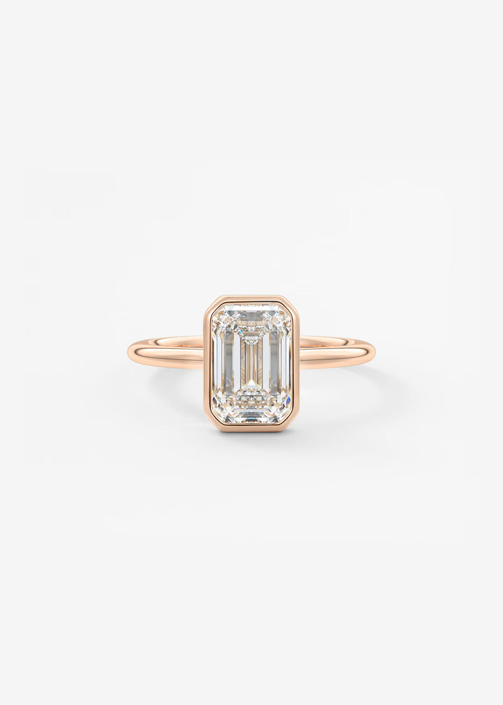 A rose gold ring featuring an emerald-cut clear diamond, set against a clean white background.#material_rose
