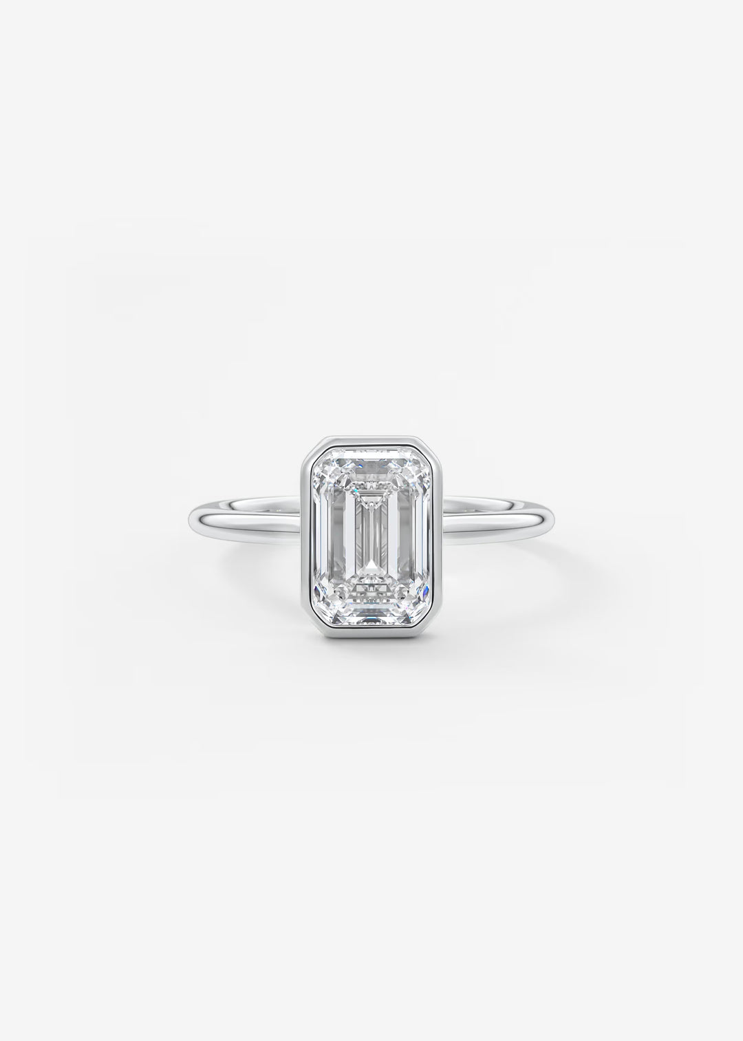 An emerald-cut diamond engagement ring in a silver-toned band, centered on a clean white background.#material_white