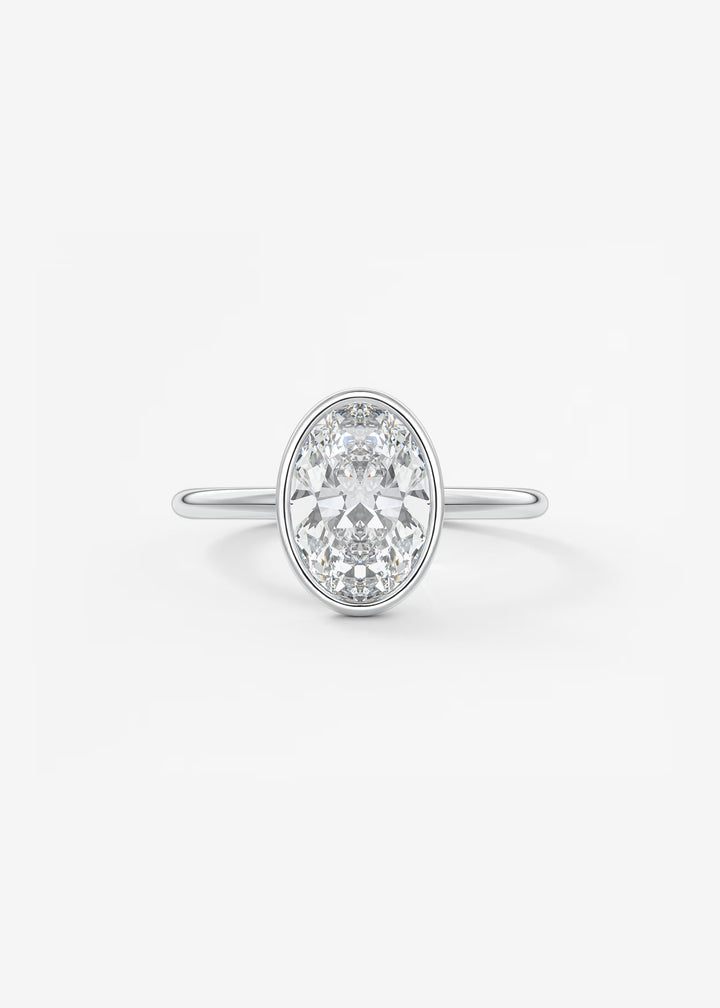 An oval diamond engagement ring with a silver-colored band, set against a clean white background.#material_white