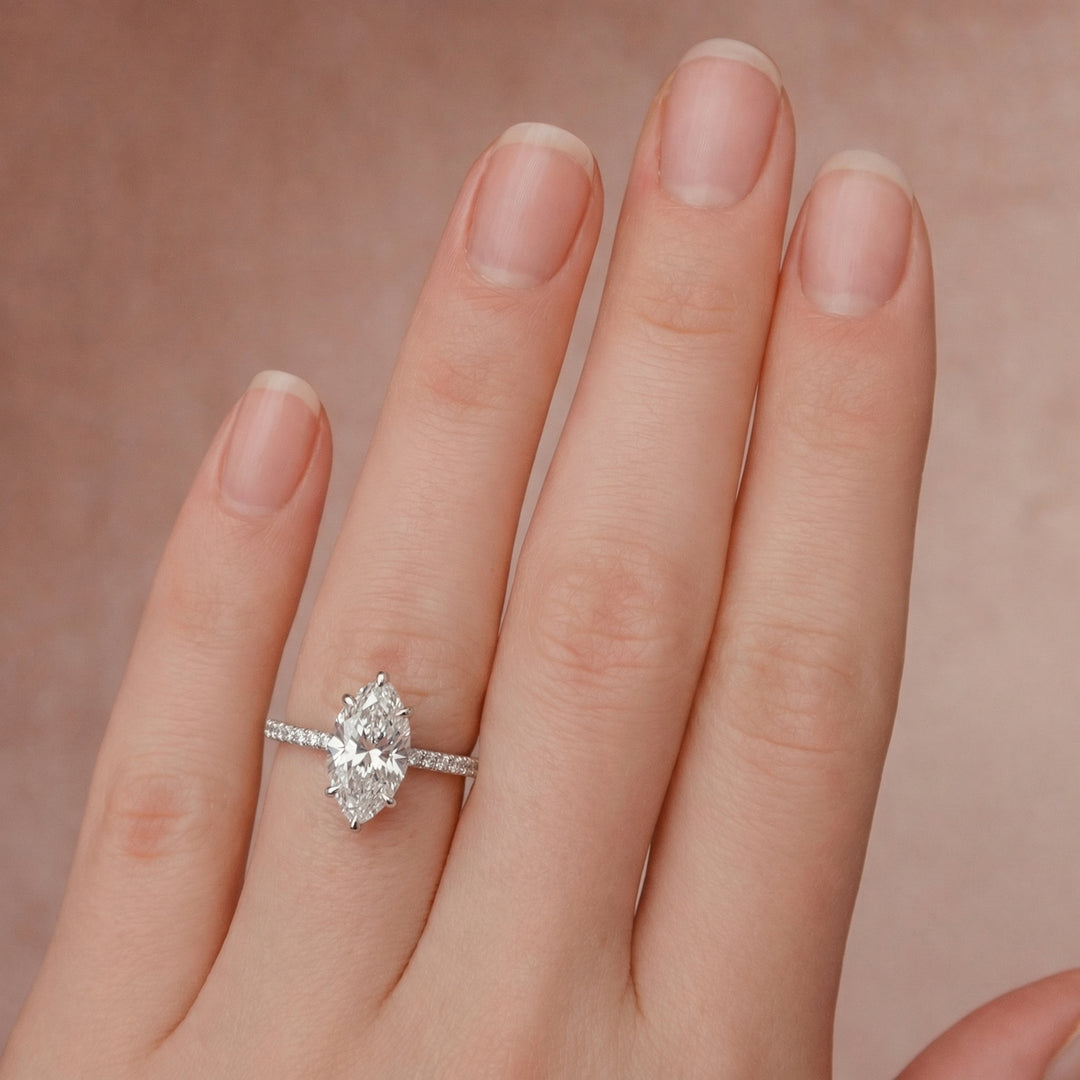 Diamond ring on a finger against a soft pink background #material_white