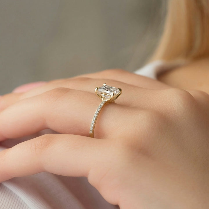 Gold ring with a diamond on a person's finger against a neutral background #material_gold