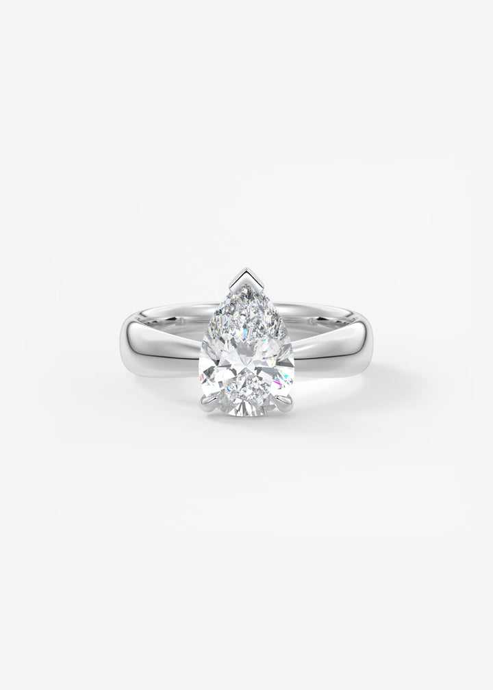 A pear-cut diamond solitaire ring set in a polished silver-colored metal band, centered on a clean white background. #material_white