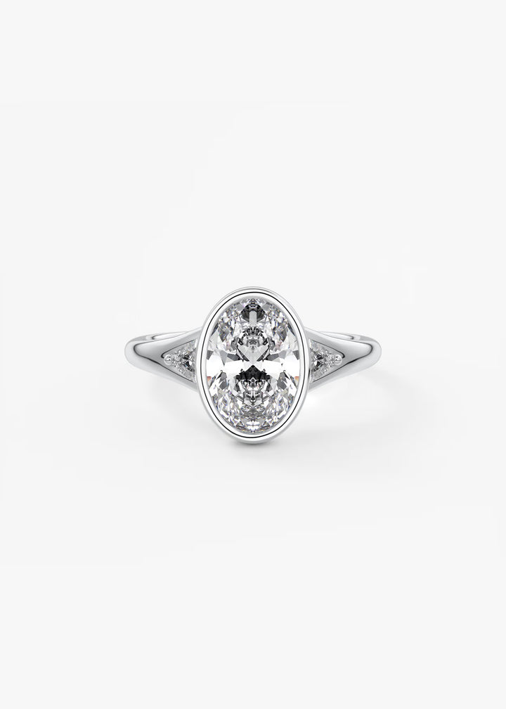 An oval-cut diamond engagement ring with a silver-toned band, photographed on a clean, light gray background.#material_white