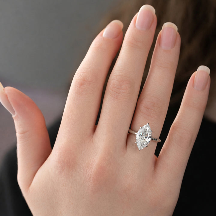 Hand wearing a diamond ring with a dark background #material_white