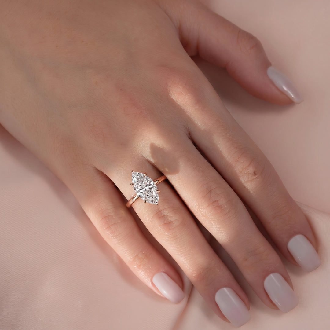 Close-up of a hand wearing a diamond ring on a soft pink background#material_rose