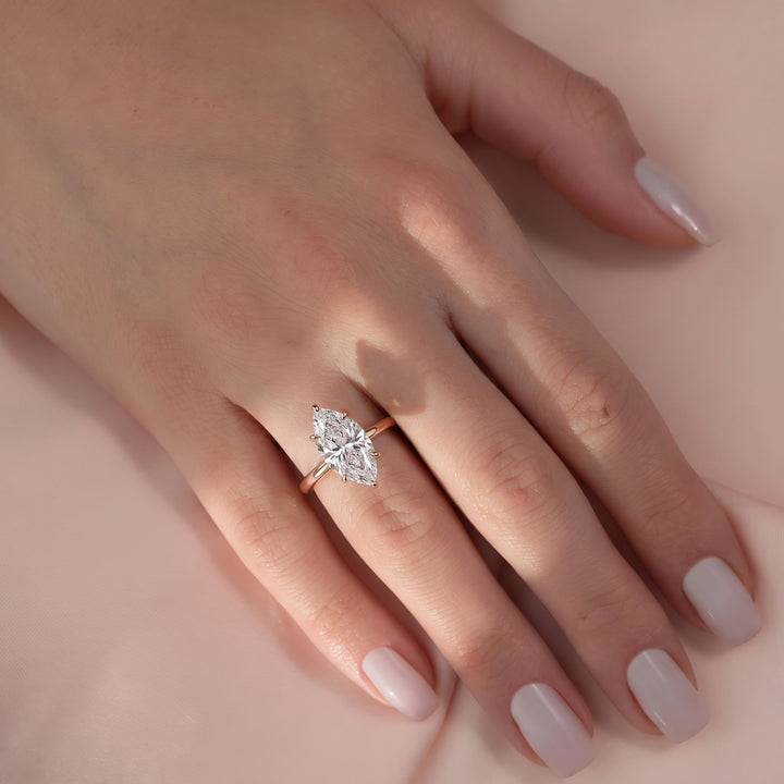 Close-up of a hand wearing a diamond ring on a soft pink background#material_rose
