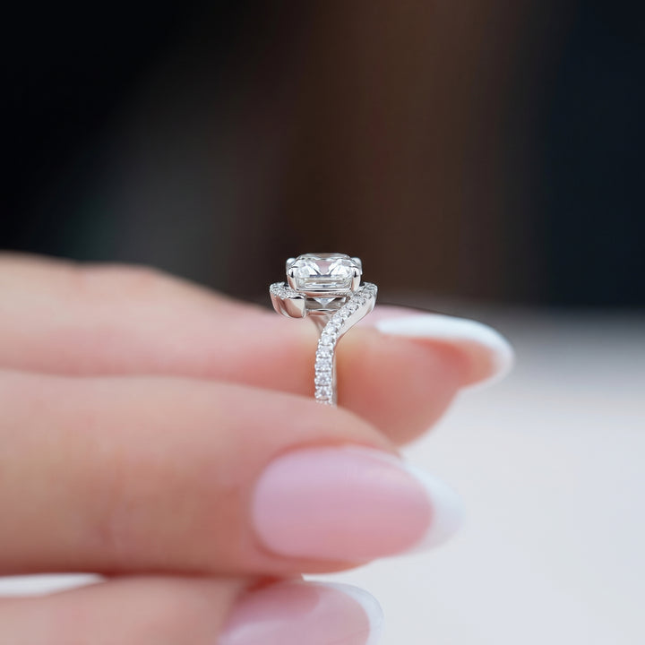 A close-up lifestyle shot of a silver-toned diamond ring held between a person's fingers with a French manicure. #material_white