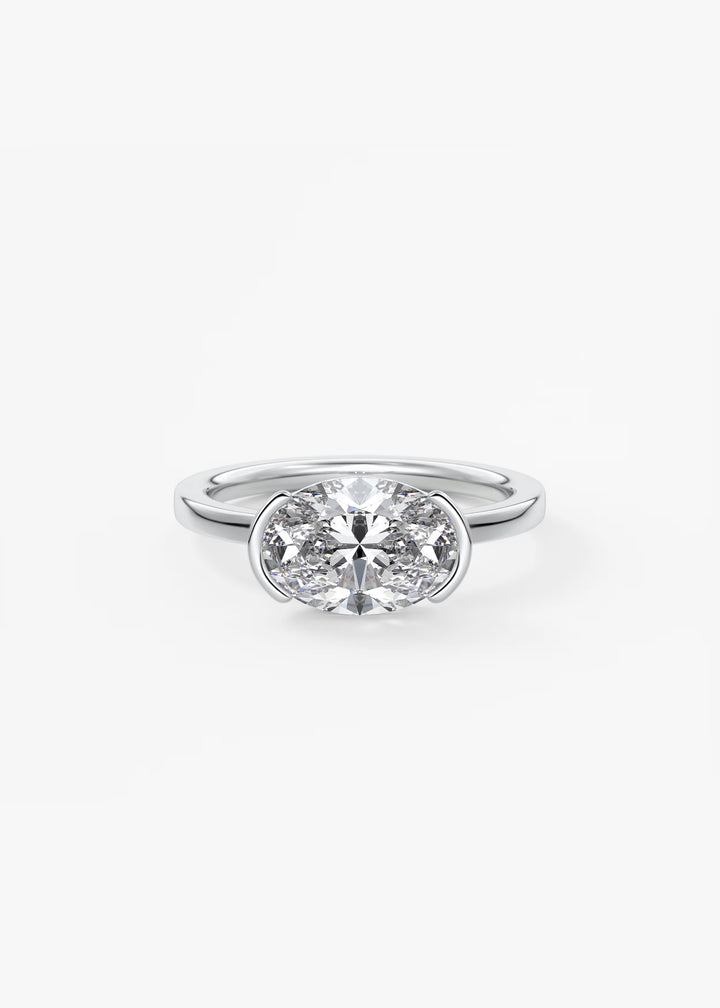 A silver solitaire engagement ring featuring a round brilliant-cut diamond in a bezel setting, shown on a clean white background.#material_white