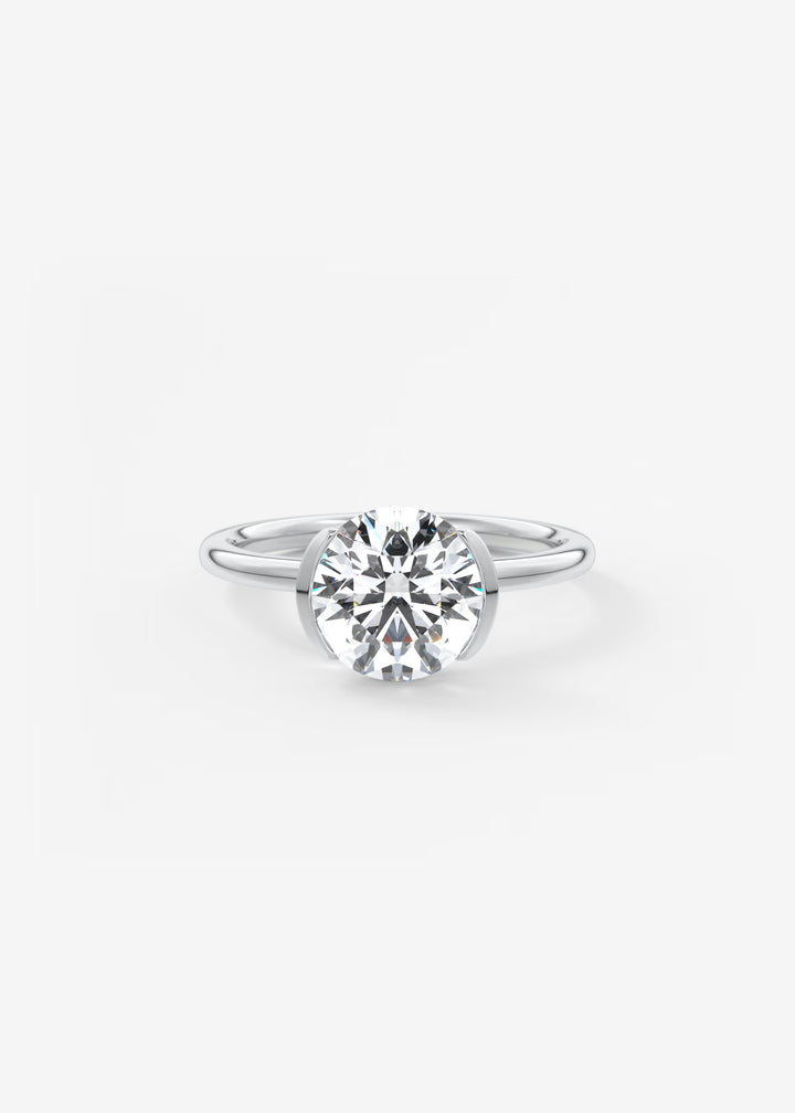 A classic solitaire engagement ring featuring a round brilliant-cut diamond set in a polished silver-colored band, centered on a clean white background.#material_white