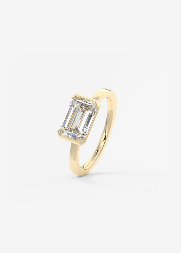The Vela East West Emerald Cut Engagement Ring with Half Bezel#material_gold